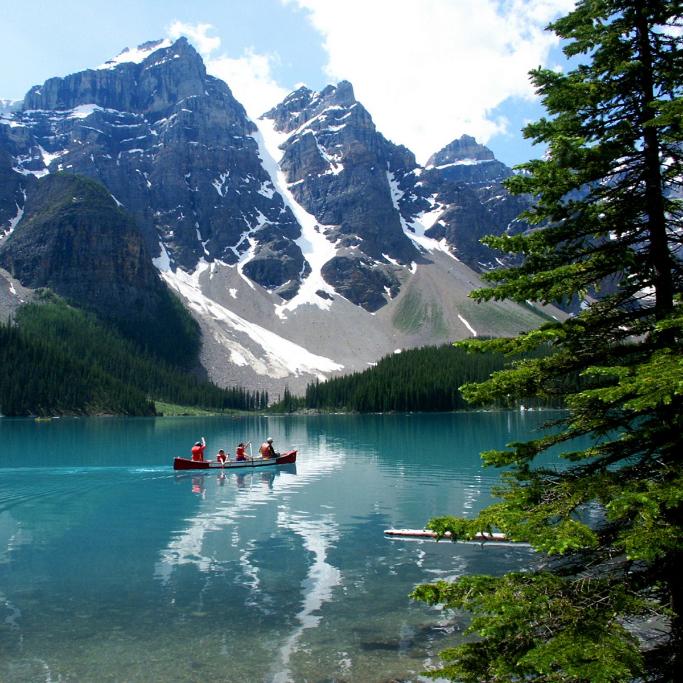 Canoe on a clear lake with mountains and trees in the background