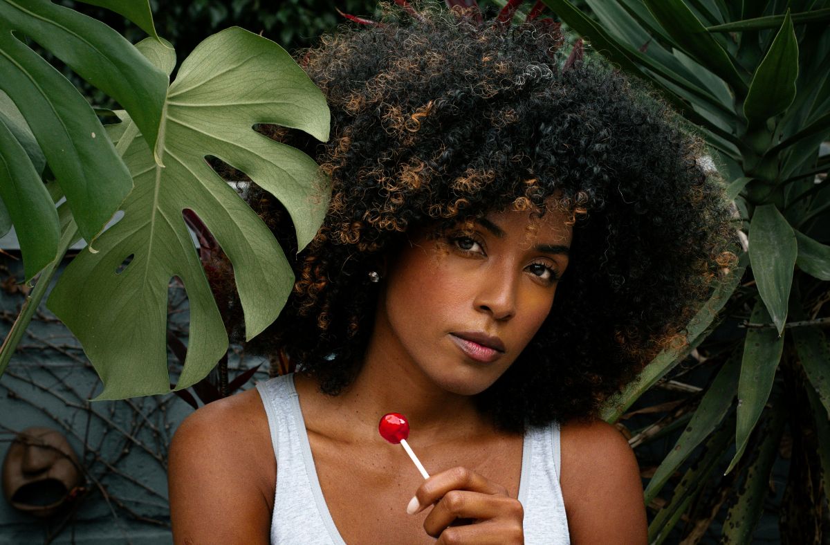 Woman holding a lollipop with green leaves in the background