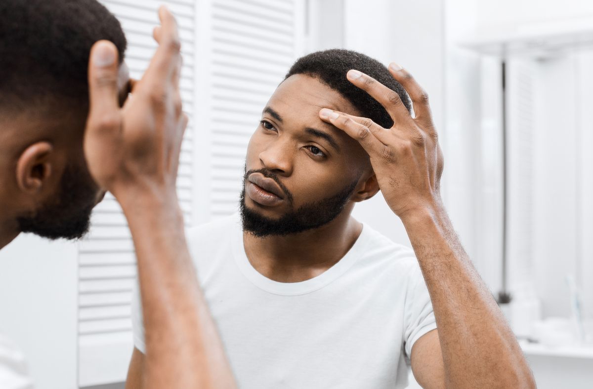 Man examining his hair in front of a mirror
