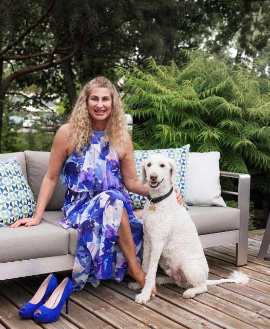 Woman in a floral dress sitting on a patio with a white dog.